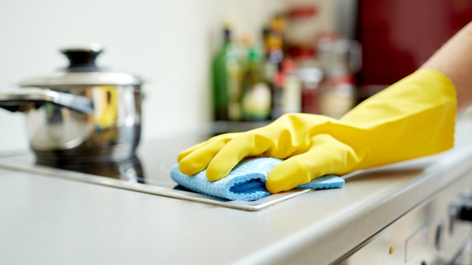 Siivooja pyyhkii rätillä hellaa.